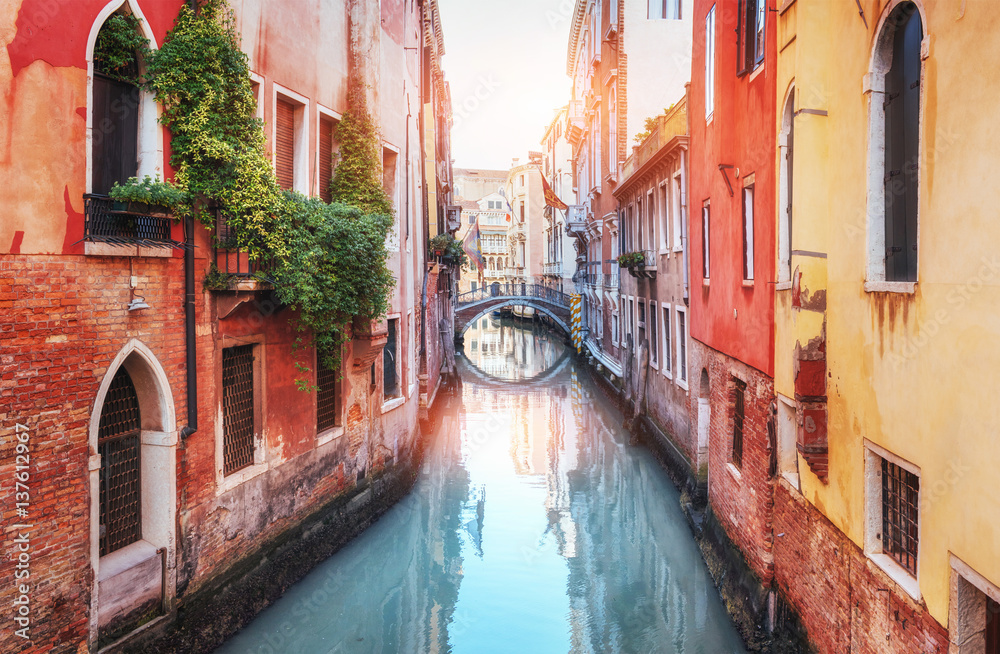 Traditional Gondolas on narrow canal between colorful historic houses in Venice Italy