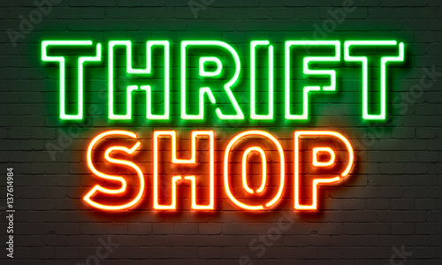 Thrift shop neon sign on brick wall background.