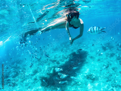 Tela Beautiful woman snorkeling among fishes in blue ocean.
