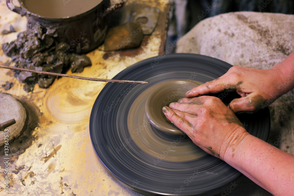 Fototapeta premium closeup of hands working on pottery wheel, clay pot 
