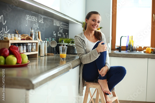 Young woman sitting a table in the kitchen .