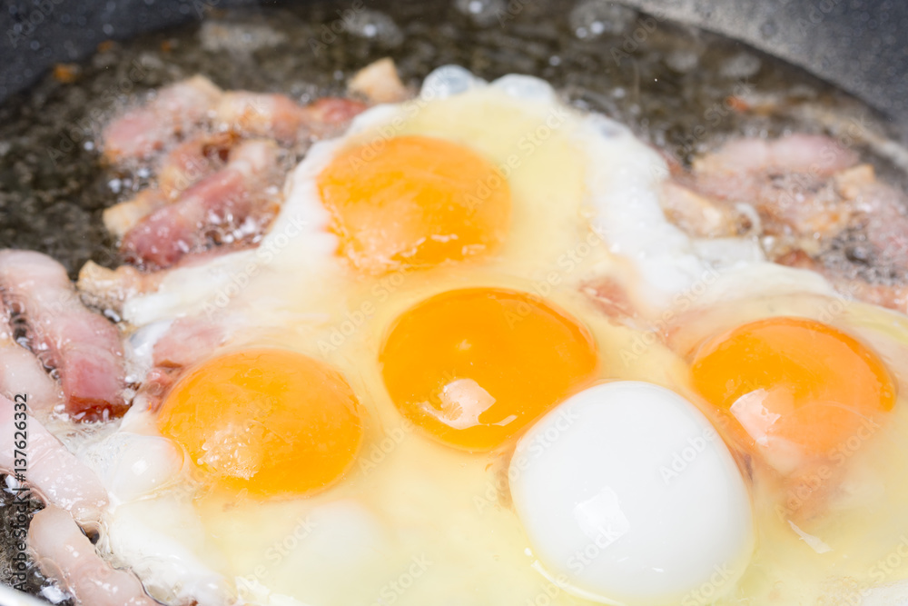 Frying eggs with sliced bacon in the hot oil Frying eggs with sliced bacon in the hot oil