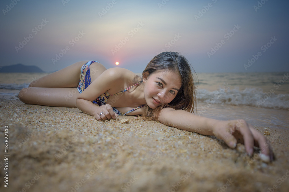 woman enjoy the beach at sunset by laying down in the rim of the sea wave