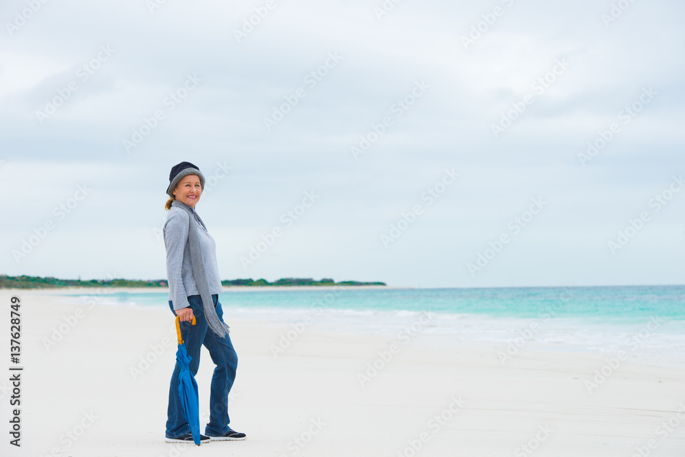 Happy mature woman with umbrella ocean background Happy mature woman with umbrella ocean background