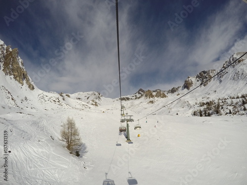 chairlift with skiers moving to the top of the mountain in a wonderful sunny day at the ski station Tonale, Ponte di Legno (Italy) photo
