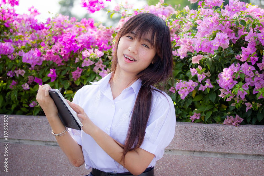 Portrait of thai high school student uniform beautiful girl using her tablet.