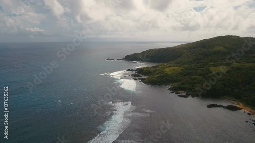 The coast of the tropical island with the mountains and the rainforest on a background of ocean with big waves.Aerial view: sea and the tropical island with rocks, beach and waves. Seascape: sky photo