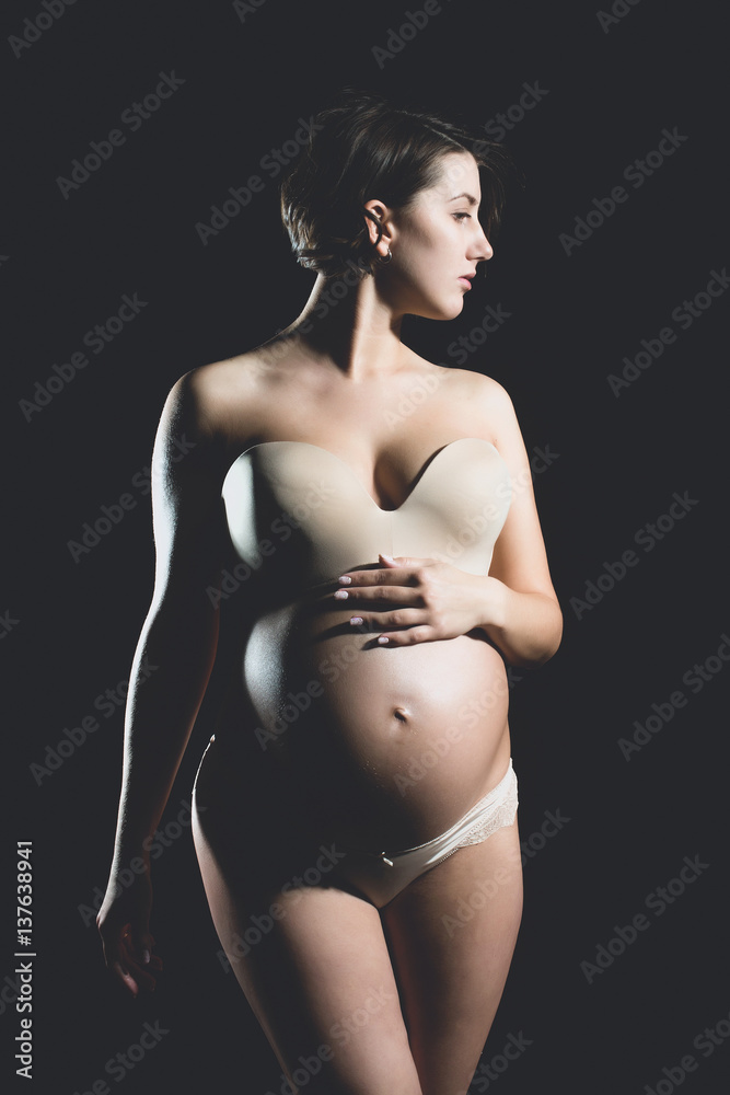 Naklejka premium pretty pregnant woman with round belly isolated on black