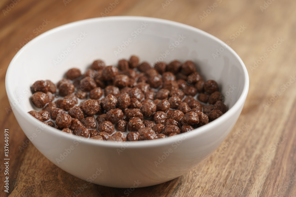 chocolate cereal balls with milk in white bowl for breakfast on wooden table chocolate cereal balls with milk in white bowl for breakfast on wooden table