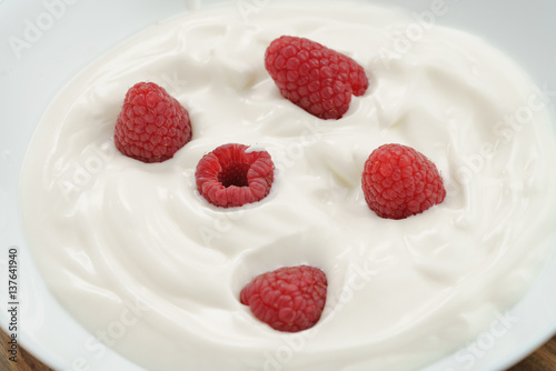 organic yogurt with fresh raspberries closeup, food background
