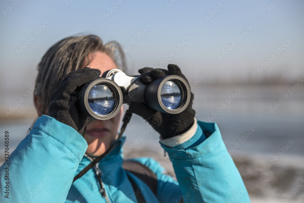 Obraz premium Woman looking through binoculars in winter landscape