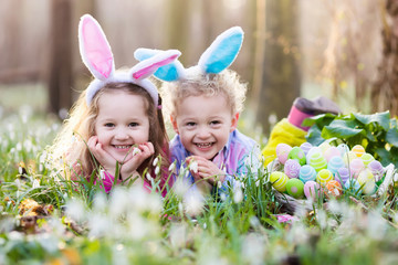 Kids on Easter egg hunt in blooming spring garden