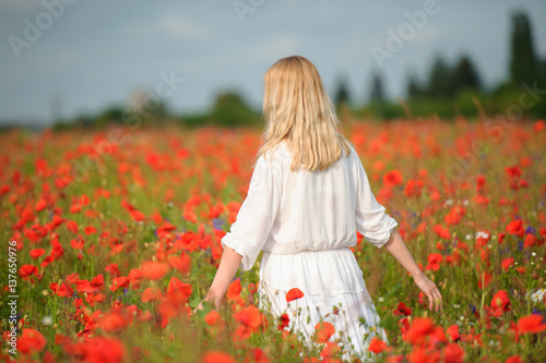woman wearing white dress at summer blooming field. Back view