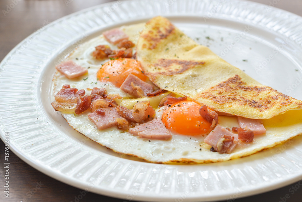 Sunny side up egg crepe on white plate
Sunny side up egg crepe on white plate