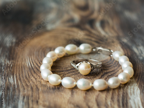 Beautiful pearl braclet and ring on wooden background. Close up