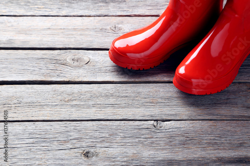 Red rubber boots on a grey wooden table