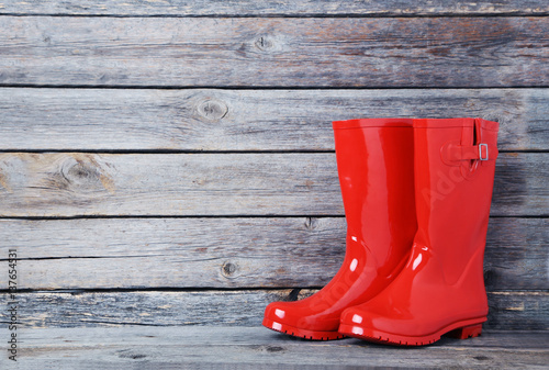 Foto Red rubber boots on a grey wooden table