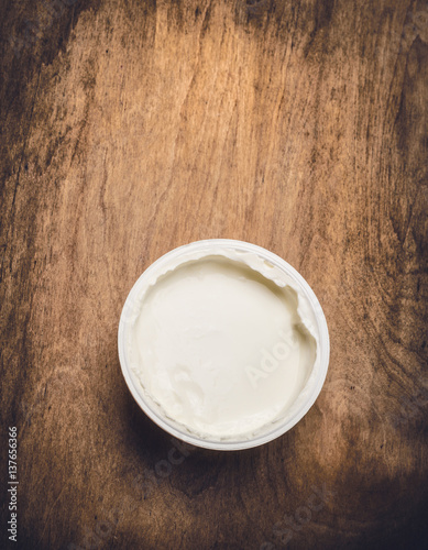 Yogurt in plastic cup on rustic wooden background, top view