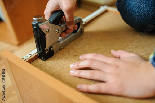 Worker repairing furniture with construction stapler
