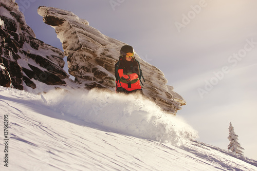 Fast snowboarder downhill in powder.