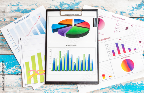 Clipboard with financial graphs and diagram on wooden table. Business background. photo