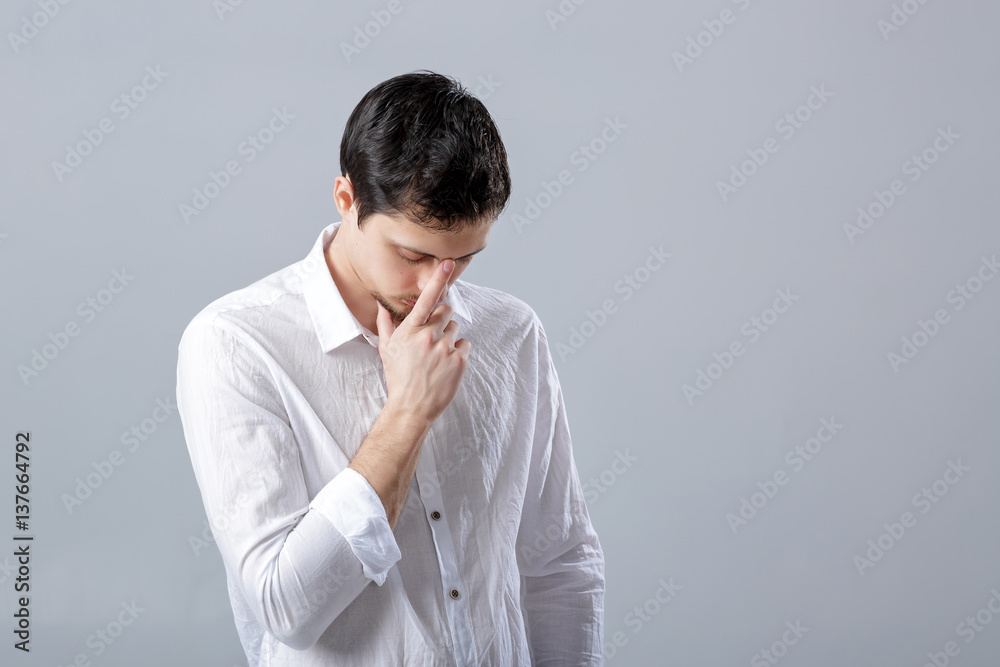 portrait of handsome young pensive man in white shirt on gray ba portrait of handsome young pensive man in white shirt on gray ba
