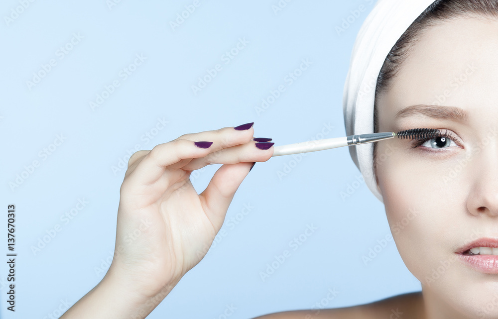 Portrait jeune femme blonde se maquillant les cils 