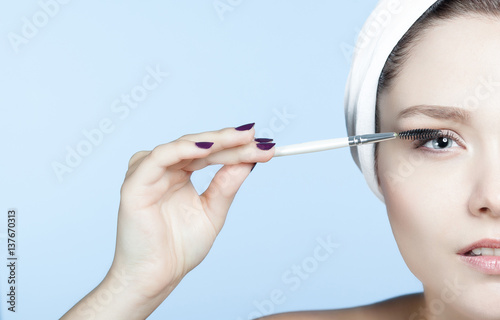 Portrait jeune femme blonde se maquillant les cils 