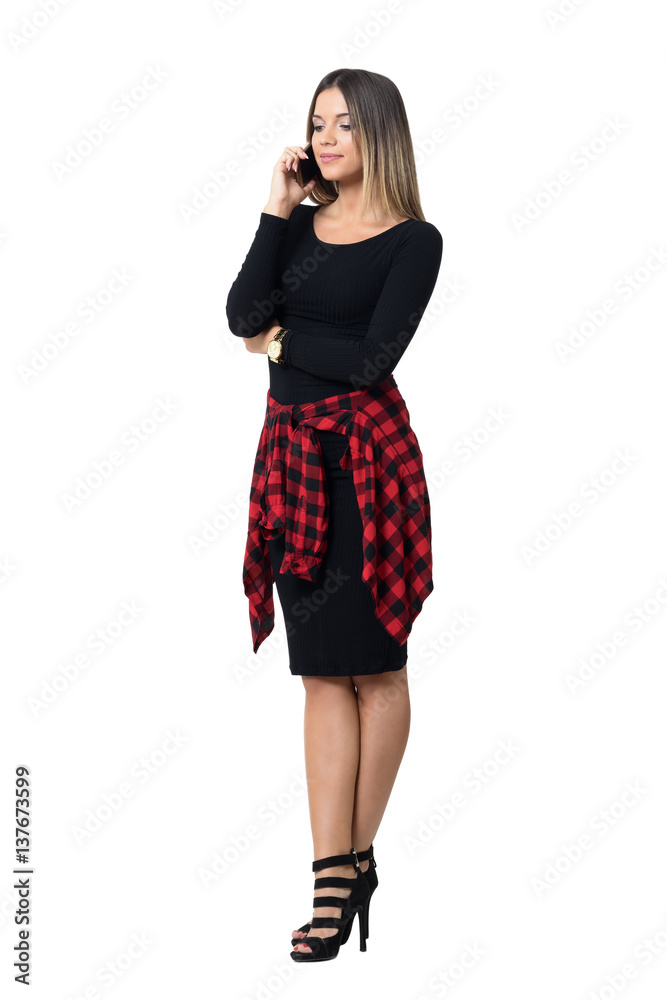 Graceful young feminine elegant woman in high heels talking on the cellphone looking down. Full body length isolated over white studio background. Graceful young feminine elegant woman in high heels talking on the cellphone looking down. Full body length isolated over white studio background.
