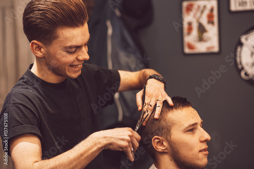 Hairdresser makes hairstyle a man with a beard