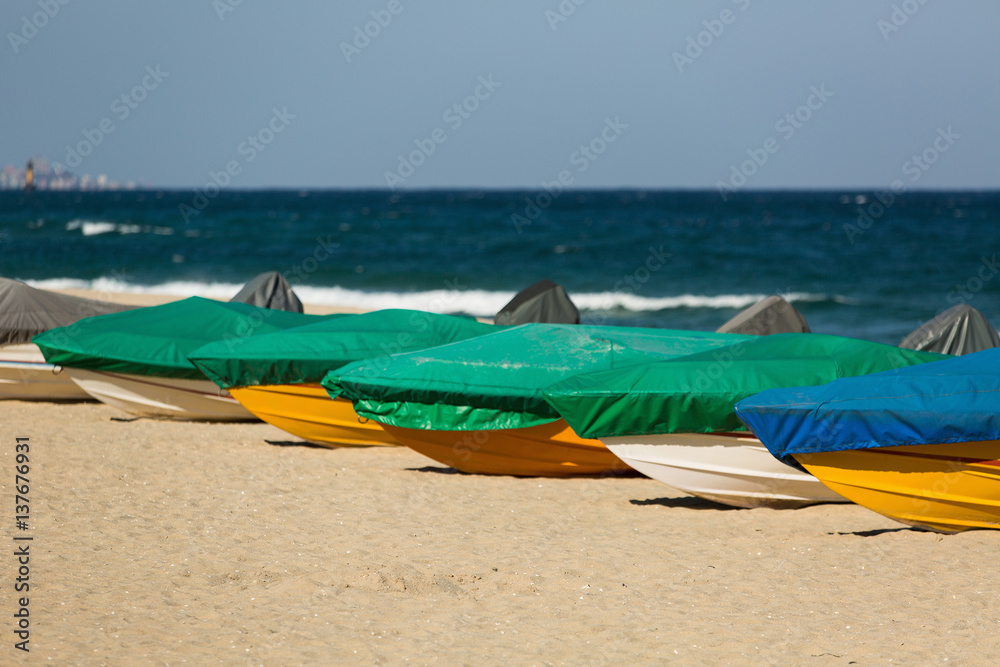 Motor boats are under the covers on a beach near the sea Motor boats are under the covers on a beach near the sea