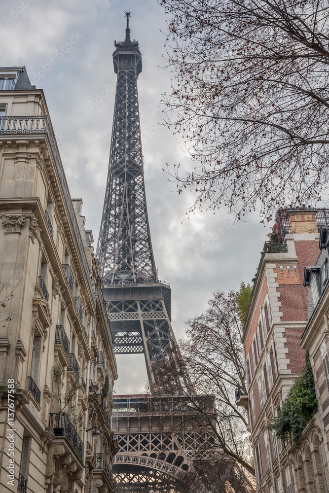 The Eiffel tower, towering over the surrounding houses on a cloudy winter day