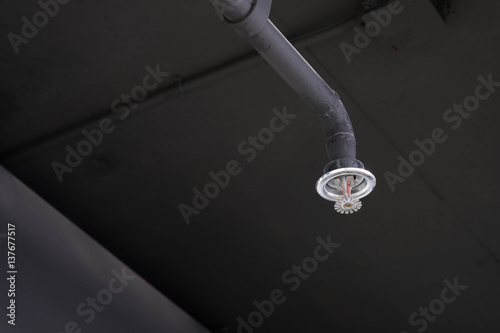 Fire sprinklers put on the black ceiling of modern office.