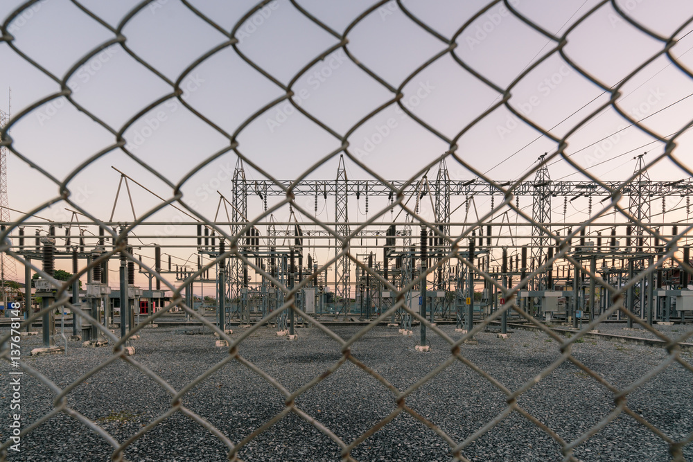 Impression network at transformer station in sunrise, high voltage up to twilight sky.
High-voltage wires and transformer - Electrical distribution station behind the wire mesh.