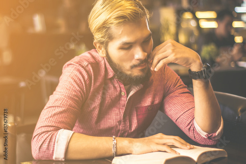 Young man reading a book at the coffee shop