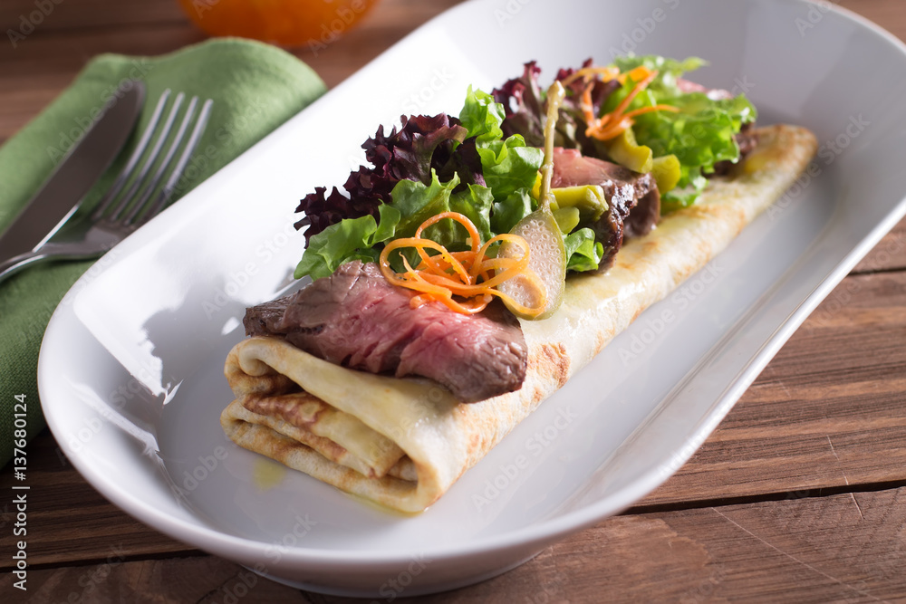 A healthy Breakfast, crepes with beef, cheese, herbs, tomatoes on a wooden table. Selective focus