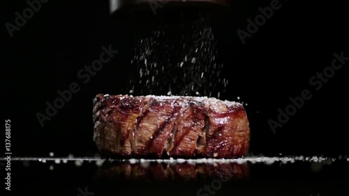 SLOW MOTION FOOD: salt falls to the filet mignon in a close up