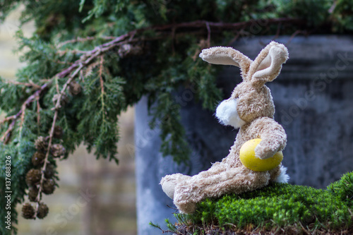Easter concept. Funny teddy rabbit with a yellow egg.