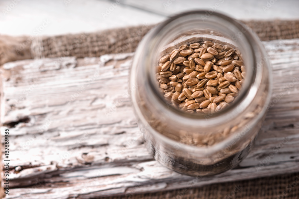Wheat seeds in a glass jar on a white rustic board side view Wheat seeds in a glass jar on a white rustic board side view