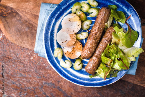 Chevanchichi with lettuce and daikon on a blue plate copy space photo