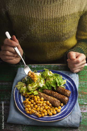 Woman eating chevanchichi, chickpeas, salade at the table photo