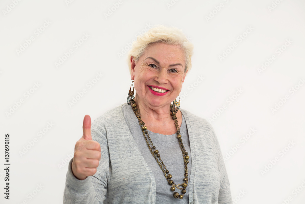 Elderly woman showing thumbs up. Smiling lady on white background. Positive mindset leads to success. Elderly woman showing thumbs up. Smiling lady on white background. Positive mindset leads to success.