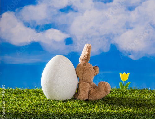 Easter scene with happy relaxed rabbit, tulip and big egg.