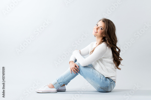 Beautiful smiling young woman sitting on the floor.