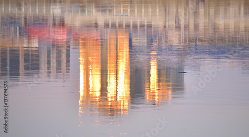 Skyscraper at sunset reflected in water.