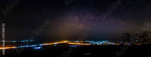 Panorama of Milky way over city lights, long exposure photograph with grain