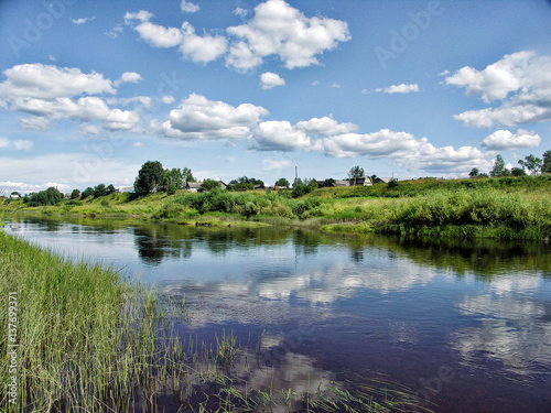 Beautiful summer rural landscape with river and clouds on the blue sky.