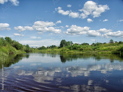 Beautiful summer rural landscape with river and clouds on the blue sky.