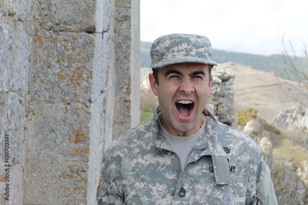 Army soldier screaming in front of some ruins 