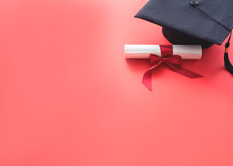 academic hat with diploma on red background